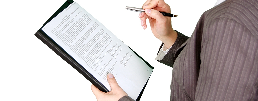 Frau, seitlich stehend mit Blick nach links, Ausschnitt Schulterausschnitt, hält Dokument in der linken Hand und Stift in der rechten Hand, um das Schriftstück zu kontrollieren. Schreibfeder zeigt zu ihr.