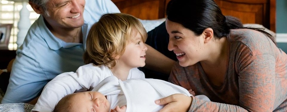 Familie mit Mutter, Vater, kleinem Jungen und Baby liegt gemeinsame auf einer Decke.